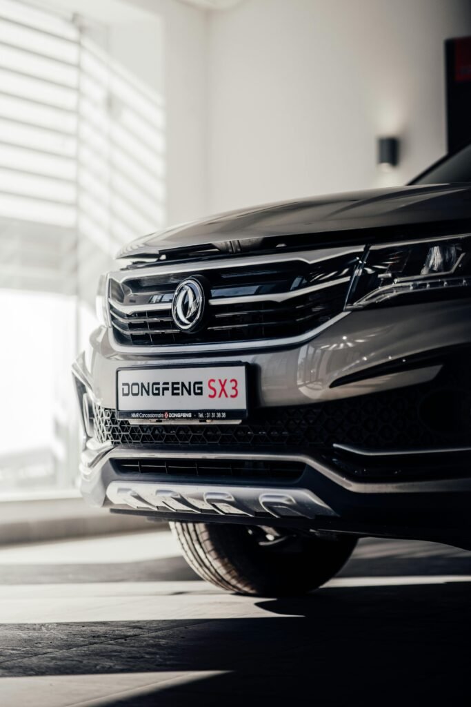 Close-up of the Dongfeng SX3 SUV front grille beautifully illuminated in a modern garage setting.