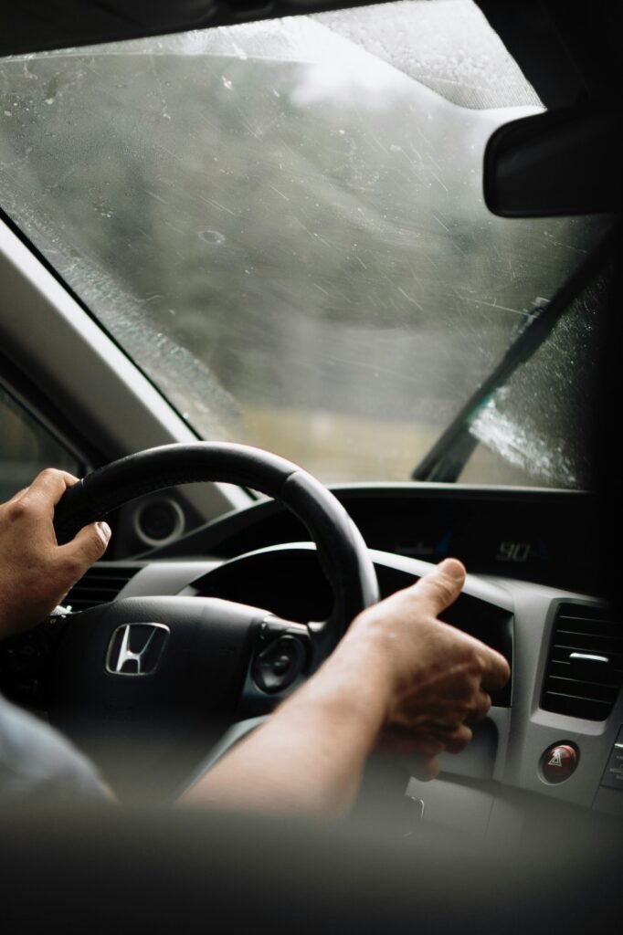 Close-up of a man's hands on a steering wheel during rain.