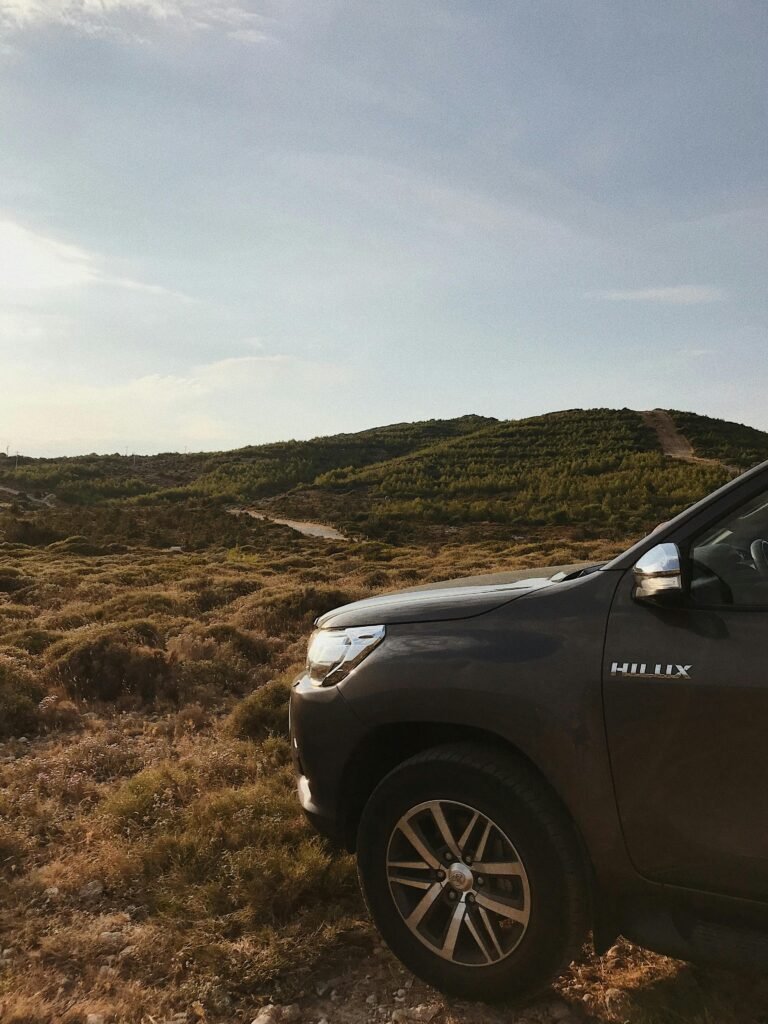 Explore rugged off-road landscapes with a Toyota Hilux parked on scenic hills at sunset.