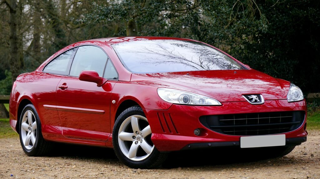 A sleek red Peugeot 407 Coupe parked outdoors, showcasing its elegant design and modern features.