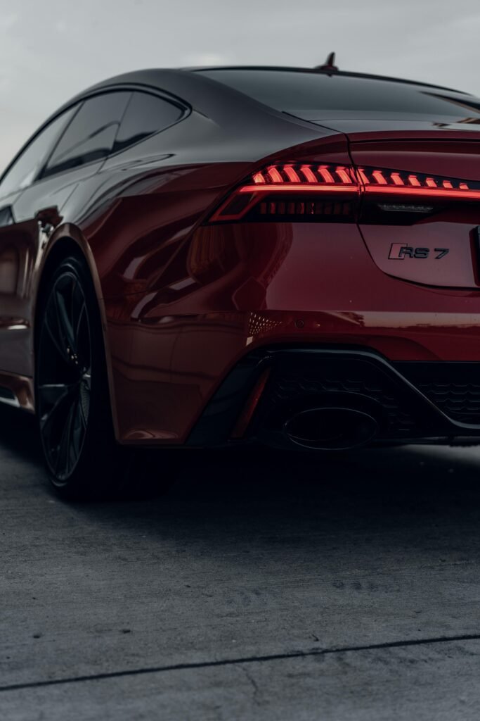 A striking red Audi RS7 sports car, captured from the back view, exhibits sleek design and elegance.